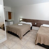 Quarto de hotel com cama, mesa de cabeceira e espelho.