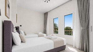 Una habitación de hotel moderna con dos camas, un ventanal grande y vistas a zonas verdes.