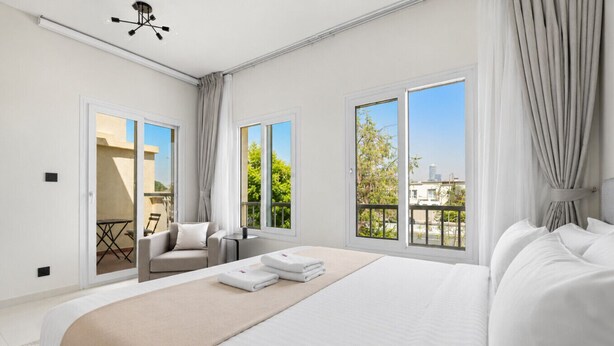 Habitación de hotel con una cama grande, un sofá, una mesita y un balcón con vistas.