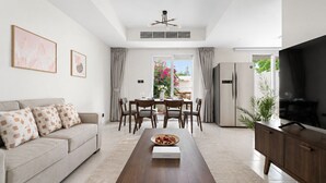 Una sala de estar moderna con un sofá, una mesa de comedor y un televisor a la derecha.