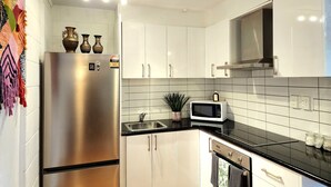 Een moderne keuken met witte kasten, roestvrijstalen apparatuur en een zwart aanrecht.