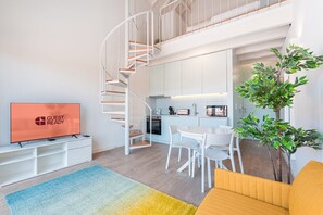 A modern apartment with a spiral staircase, a kitchen, a dining area, and a living room with a TV. - GuestReady - One lovely studio in downtown (Porto)