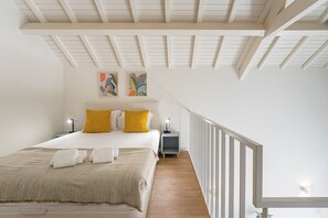 A bedroom with a bed, a nightstand, a lamp, a railing, and artwork on the wall. - GuestReady - One lovely studio in downtown (Porto)
