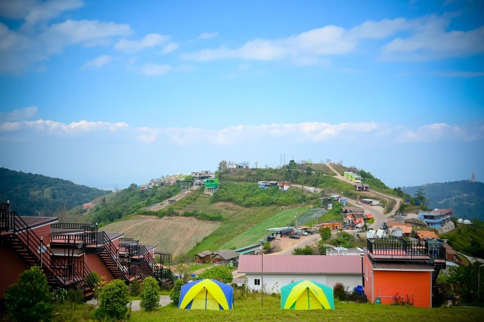 Un pueblo en una ladera con una iglesia destacada en la cima, una carretera principal y algunos edificios con escaleras visibles.