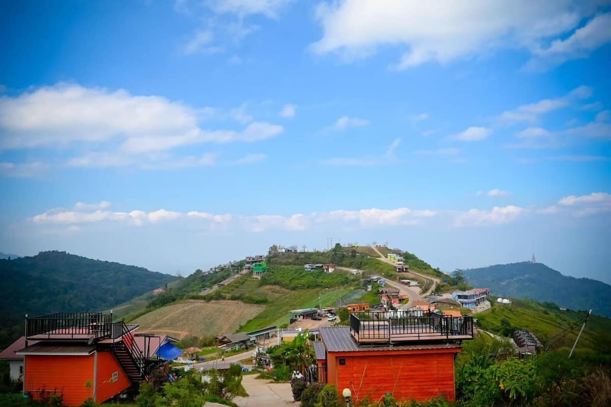 A hillside village with houses, a prominent hilltop structure, and a clear blue sky.