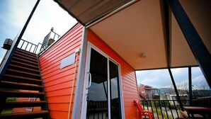 A red building with a sliding glass door, a staircase, and a covered outdoor area with a table and chairs. - Rai Rak Doi Phutubberk (Lom Kao)
