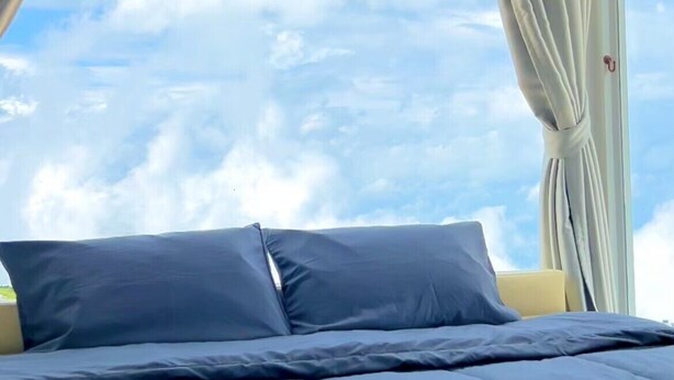 A bedroom with a bed, curtains, and a view of the sky. - Rai Rak Doi Phutubberk (Lom Kao)