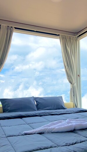 A bedroom with a bed, curtains, and a view of the sky. - Rai Rak Doi Phutubberk (Lom Kao)