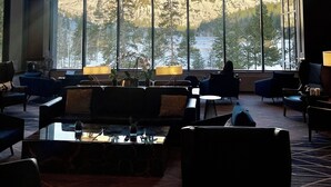 Un hall d’entrée spacieux, doté de grandes fenêtres offrant une vue sur les montagnes, de meubles modernes et d’un lustre.