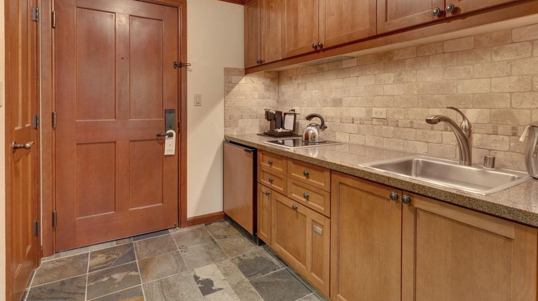 A kitchen with wooden cabinets, a granite countertop, a sink, and a coffee maker.