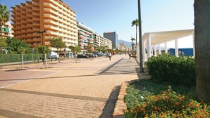 Une promenade en bord de mer bordée d’immeubles à plusieurs étages, d’une allée couverte et d’un ciel dégagé.