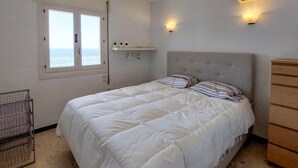 Une chambre à coucher avec un lit, une commode, une fenêtre et une étagère avec des plantes.