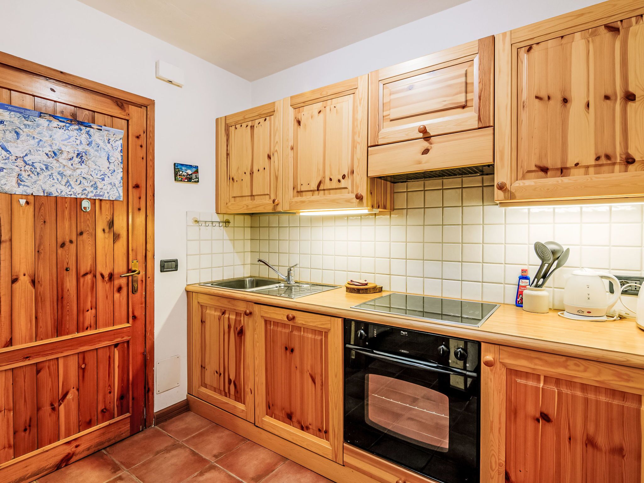 A kitchen with wooden cabinets, a stainless steel sink, and a black oven.