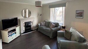 A living room with a fireplace, a television, and a sofa. - Close to beach, town, golf & natural beauty spots (Montrose)