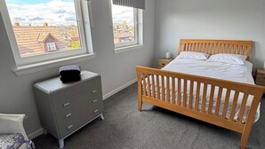 A bedroom with a wooden bed, a grey dresser, and two windows with blinds. - Close to beach, town, golf & natural beauty spots (Montrose)