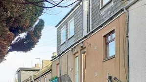 A row of townhouses with a brick facade, visible windows, and a tree in the foreground. - Close to beach, town, golf & natural beauty spots (Montrose)