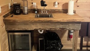 Een kleine keuken met een magnetron, koffiezetapparaat en een spoelbak.