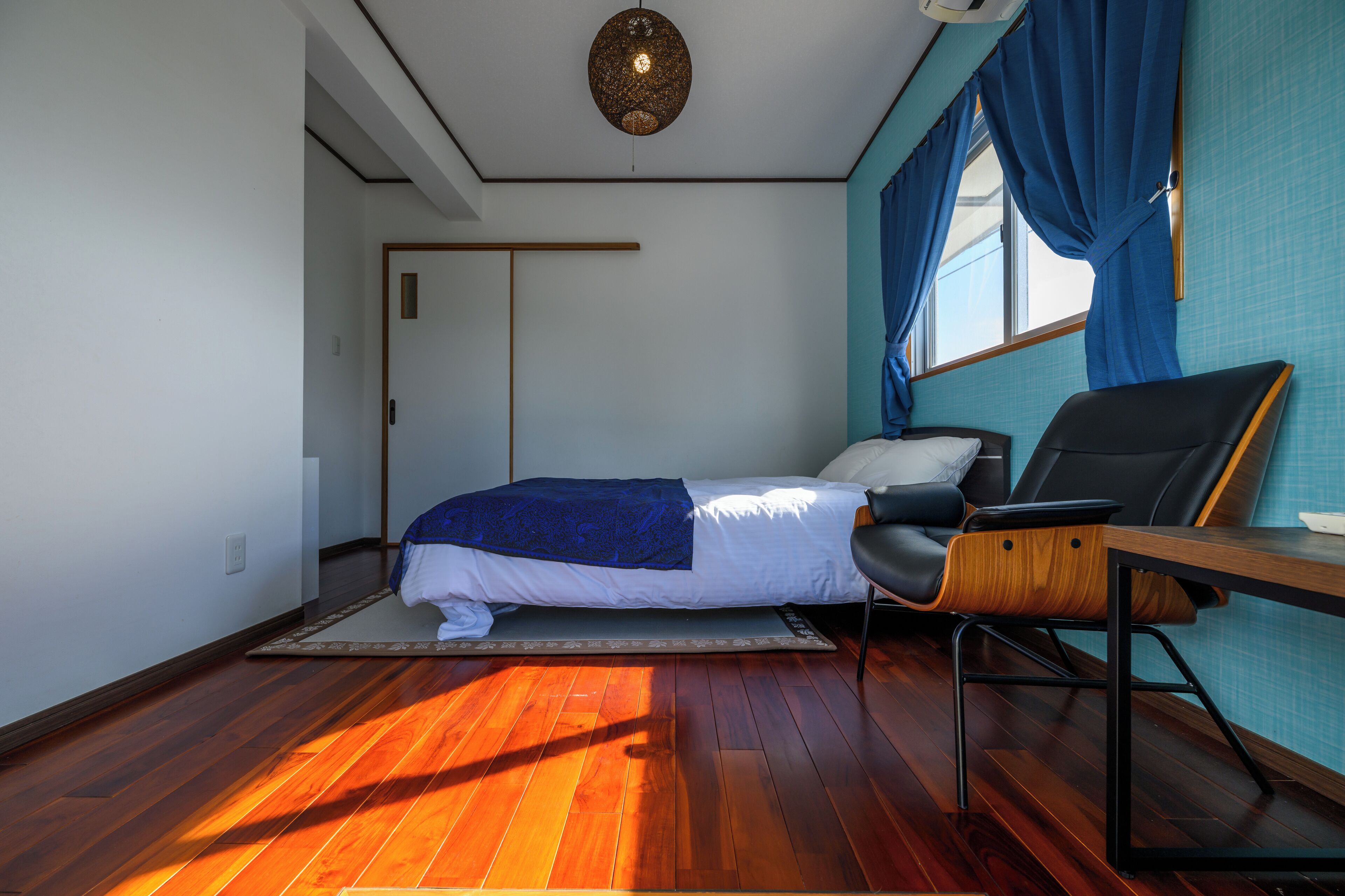 Une chambre à coucher avec un lit, un bureau, une chaise et une fenêtre avec des rideaux.