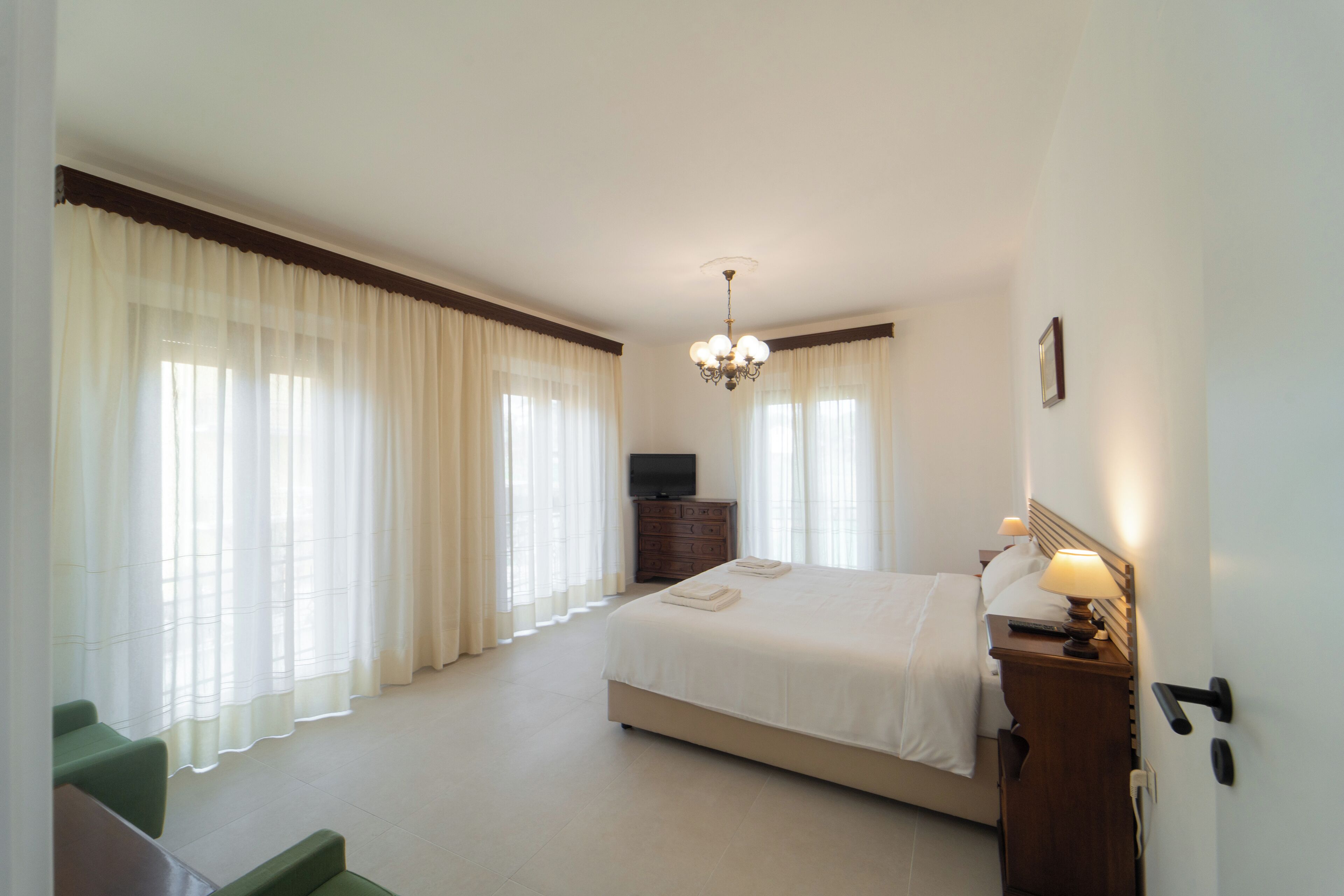 Een hotelkamer met een groot bed, een televisie, een dressoir en een stoel.
