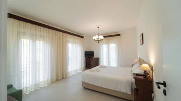 Een hotelkamer met een groot bed, een televisie, een dressoir en een stoel.