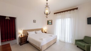 Una camera da letto ordinata con un letto grande, lampade sui comodini, una poltrona verde e un quadro appeso al muro.