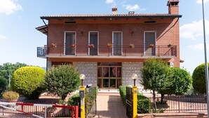 A two-story brick building with a balcony, a gated entrance, and well-maintained landscaping.