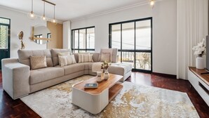A modern living room with a sectional sofa, a coffee table, and large windows. - Glimpse of the City by Homie (Funchal)