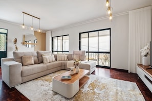 A modern living room with a sectional sofa, a coffee table, and large windows. - Glimpse of the City by Homie (Funchal)