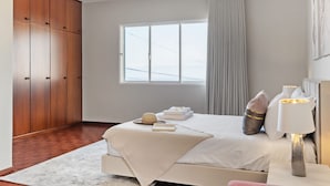 Ein Schlafzimmer mit einem Bett, einem Kleiderschrank, einem Fenster und einer Nachttischlampe.