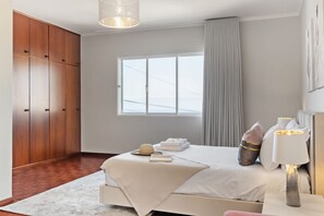 A bedroom with a bed, a wardrobe, a window, and a bedside lamp. - Glimpse of the City by Homie (Funchal)