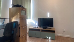 A room with a wooden desk, a chair, a television on a stand, and a cabinet. - Luxurious Entire Home, Leicester Square, Covent Garden, Tottenham Court Road (London)