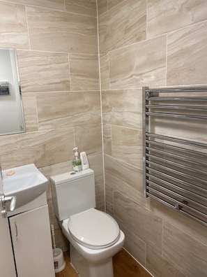 Een badkamer met beige tegels, een toilet, een wastafel en een handdoekhouder.