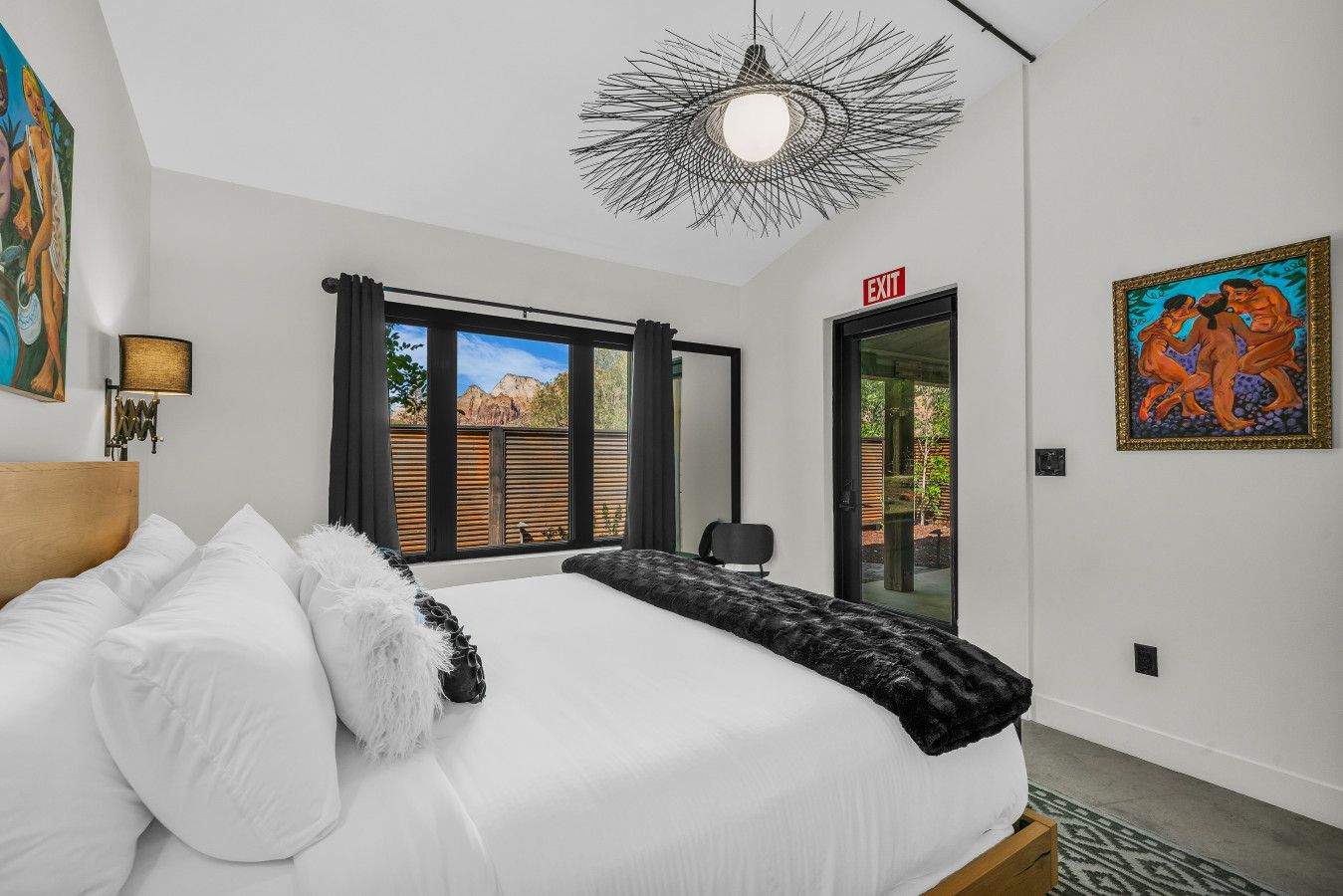 Een moderne slaapkamer met een groot bed, uitzicht op de omgeving en kunstwerken aan de muur.