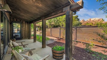 Eine überdachte Terrasse mit Holzmöbeln und Pflanzgefäßen.