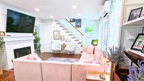 A living room with a fireplace, a television, a staircase, and a sofa.