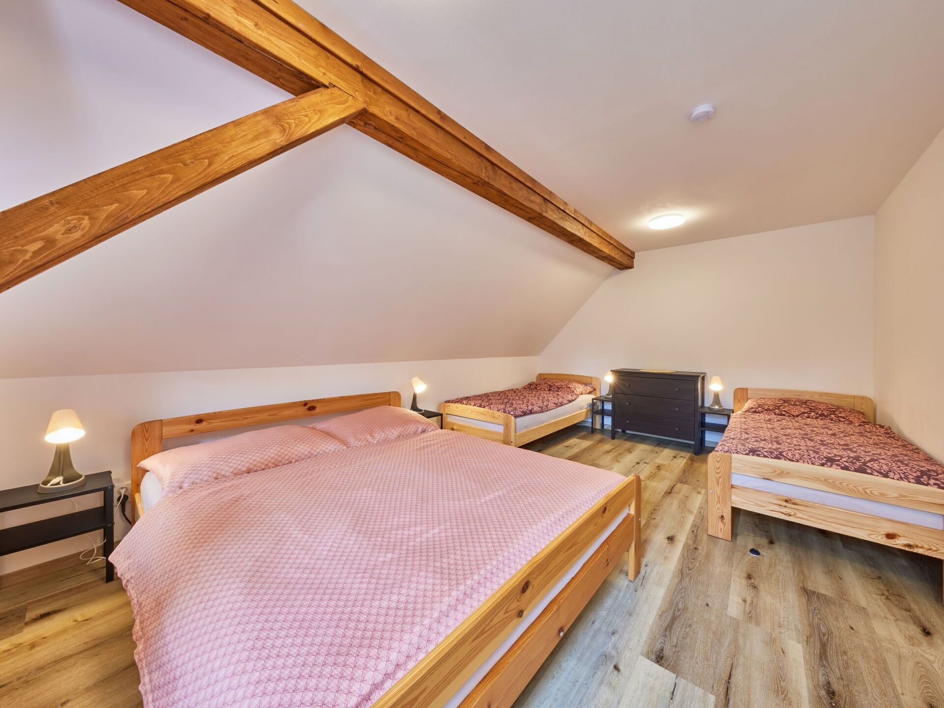 Een kamer met twee houten bedden, een kaptafel en een lamp.