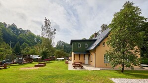 Un chalet doté d’un toit végétalisé, d’un patio couvert et d’une cour verdoyante avec des tables de pique-nique.