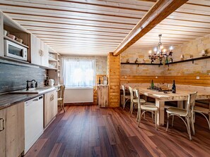 Een keuken met houten kastjes, een magnetron en een eethoek met een tafel en stoelen.