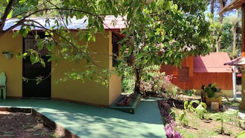 Stroll through the serene gardens to the charming building with a red roof and yellow facade.