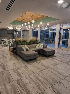 Relax in a comfortable living area with a sectional sofa and round coffee table, perfect for unwinding and enjoying the views through large windows.