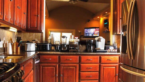 A kitchen with wooden cabinets, a stainless steel refrigerator, a stove, and a coffee maker. - Efficient and Modern home, Sleeps 8. Theres an airmattress that sleeps 2. (Oklahoma City)