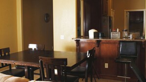 A dining area with a wooden table and chairs, a kitchen area with a refrigerator and cabinets, and a small bar area with stools. - Efficient and Modern home, Sleeps 8. Theres an airmattress that sleeps 2. (Oklahoma City)