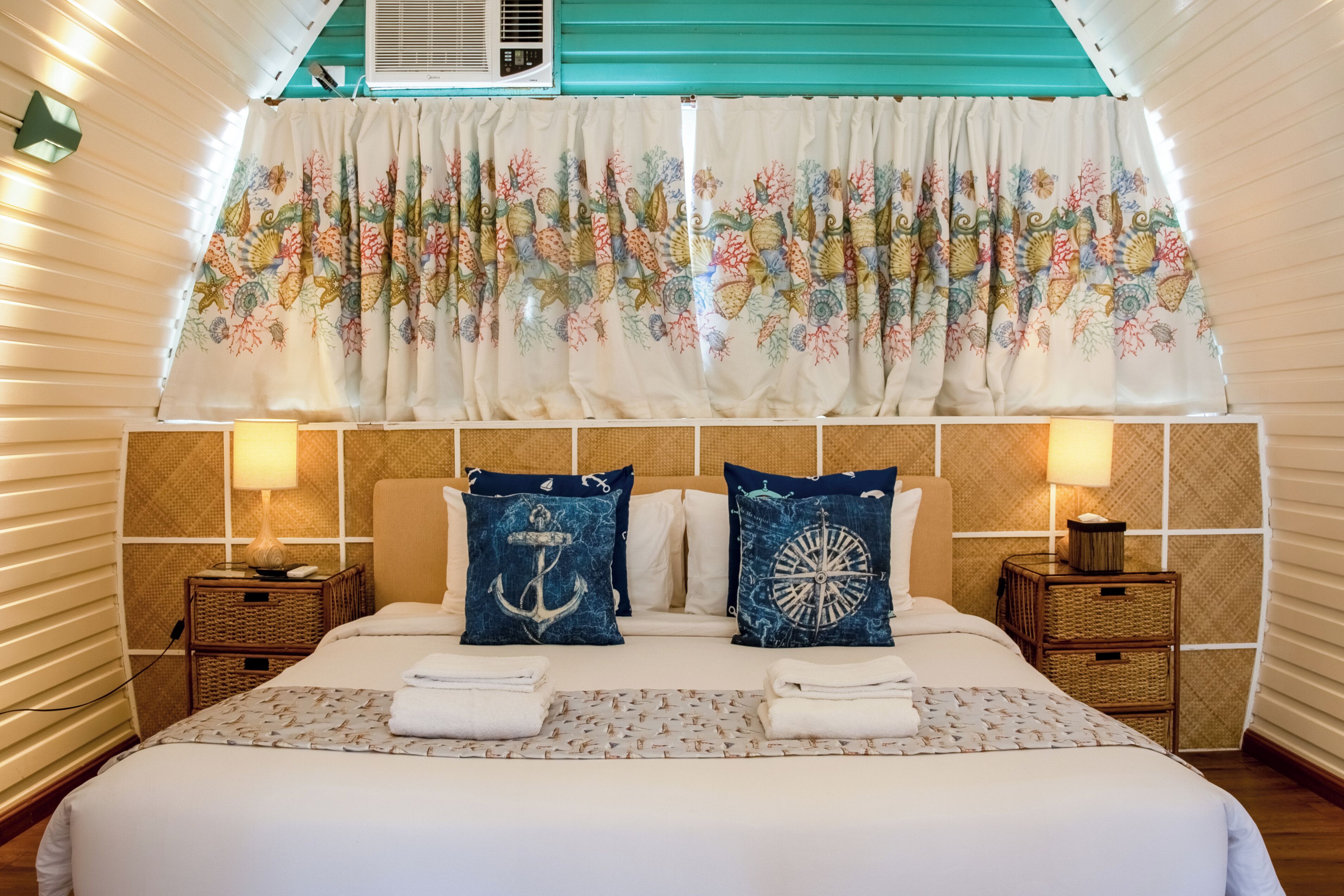 A hotel room with a bed, two nightstands, a window with curtains, and a ceiling fan.