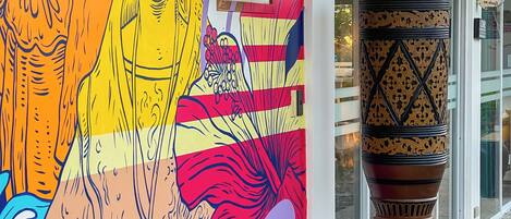 A colorful mural with abstract figures and a decorative column outside a building.