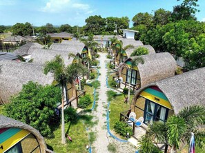 A resort with thatched-roof cottages, a central pathway, and lush greenery. - UNWND Boutique Hotel Calatagan (Calatagan)