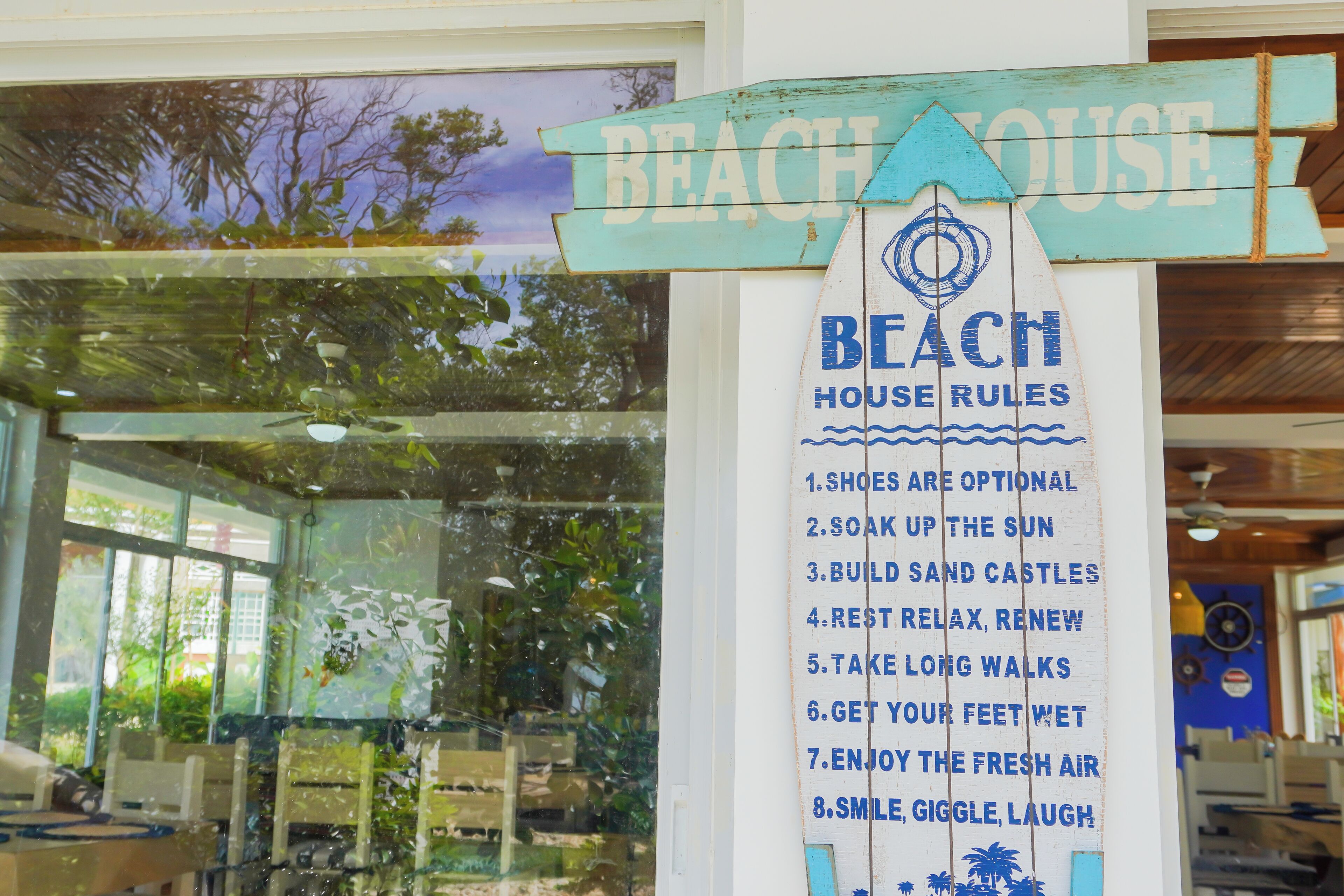 A sign with 'BEACH HOUSE RULES' and a list of activities.