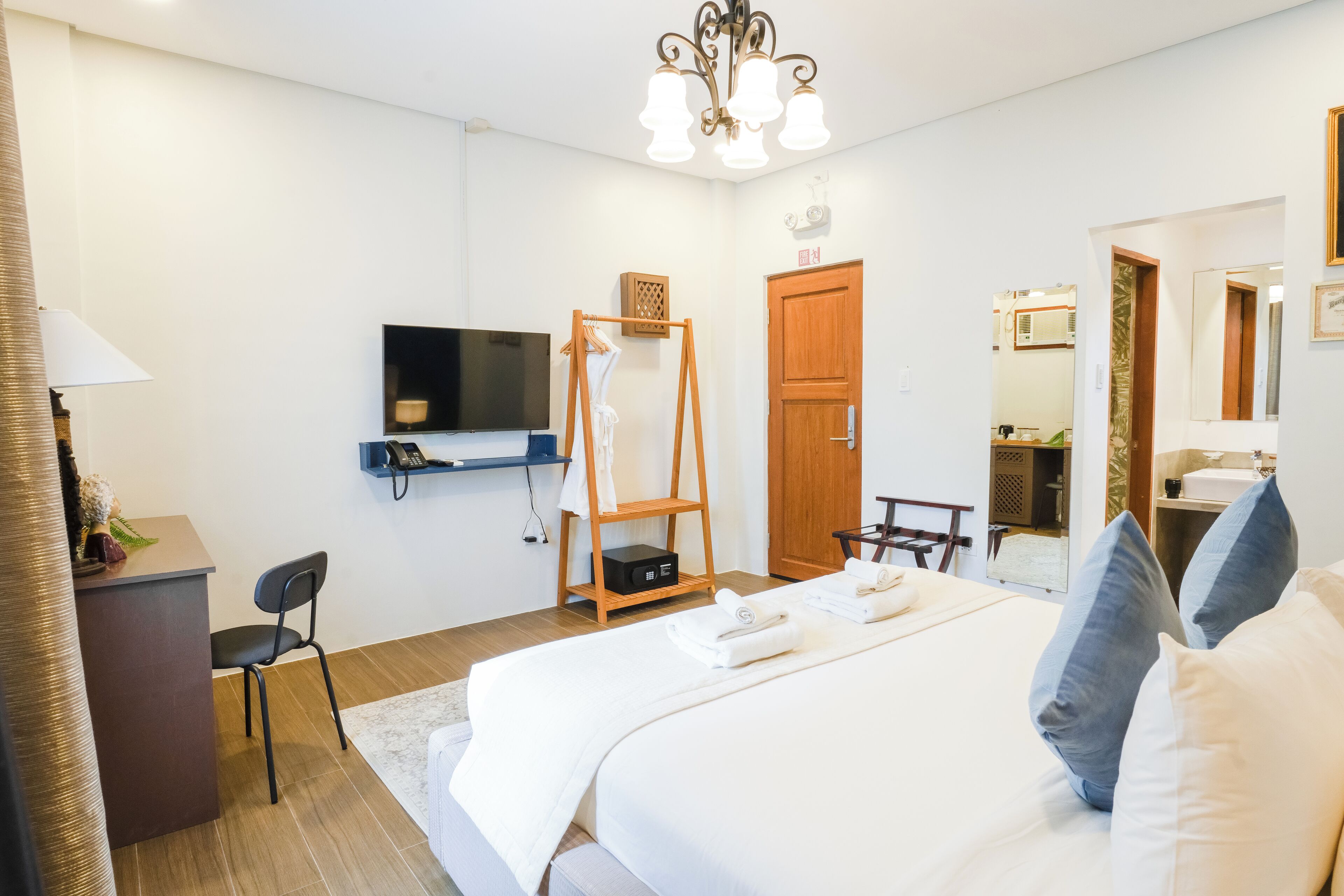Una habitación de hotel con cama, televisión, estante de madera, escritorio y silla.