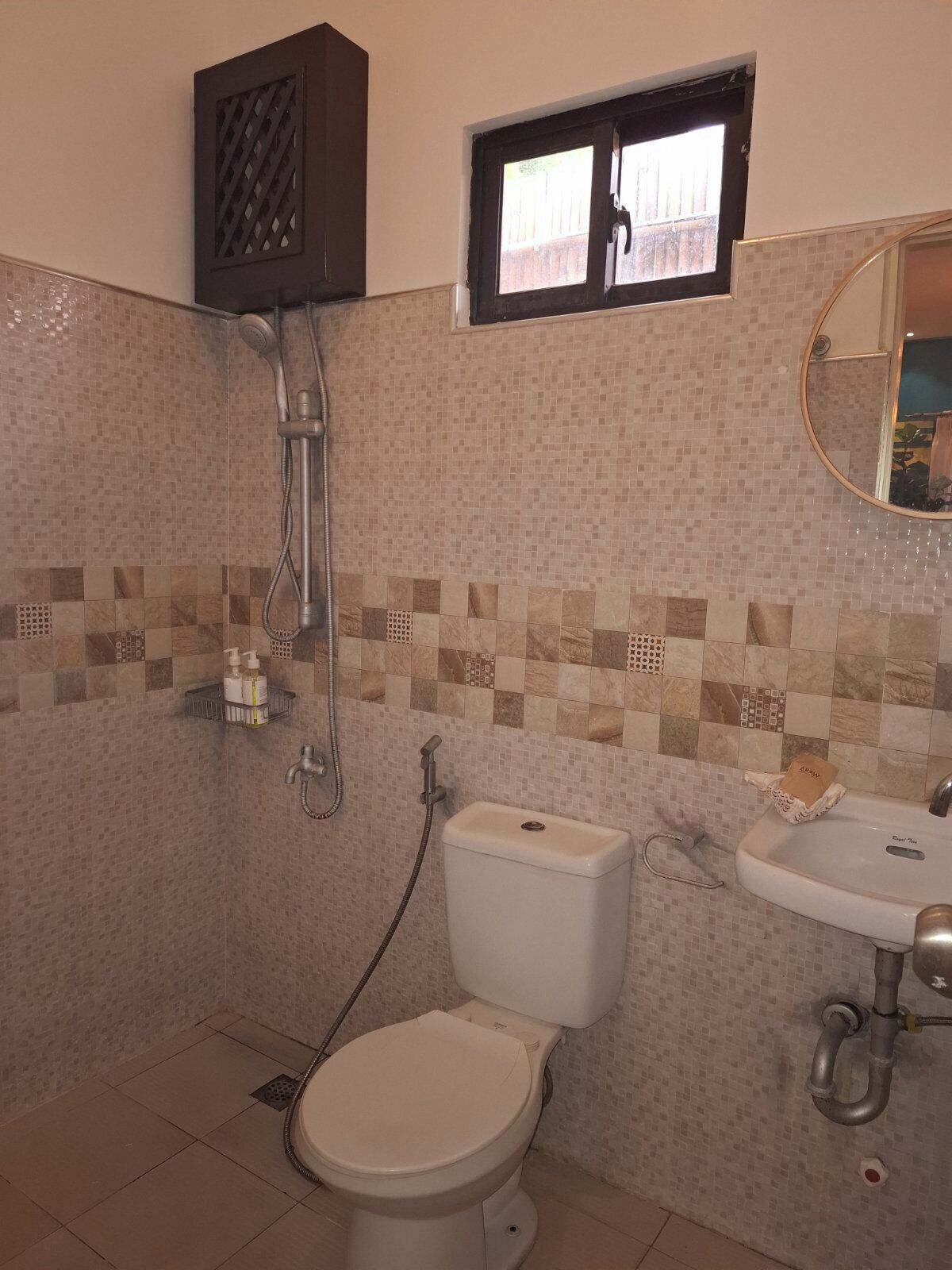 Een badkamer met toilet, wastafel, douche en een raam.