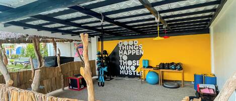 A gym with wooden structures, exercise equipment, and a motivational quote on the wall.