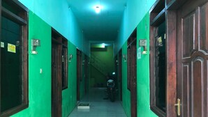 A corridor with green walls, wooden doors, and a tiled floor. - Hotel O Homestay Pak To Syariah (Surabaya)